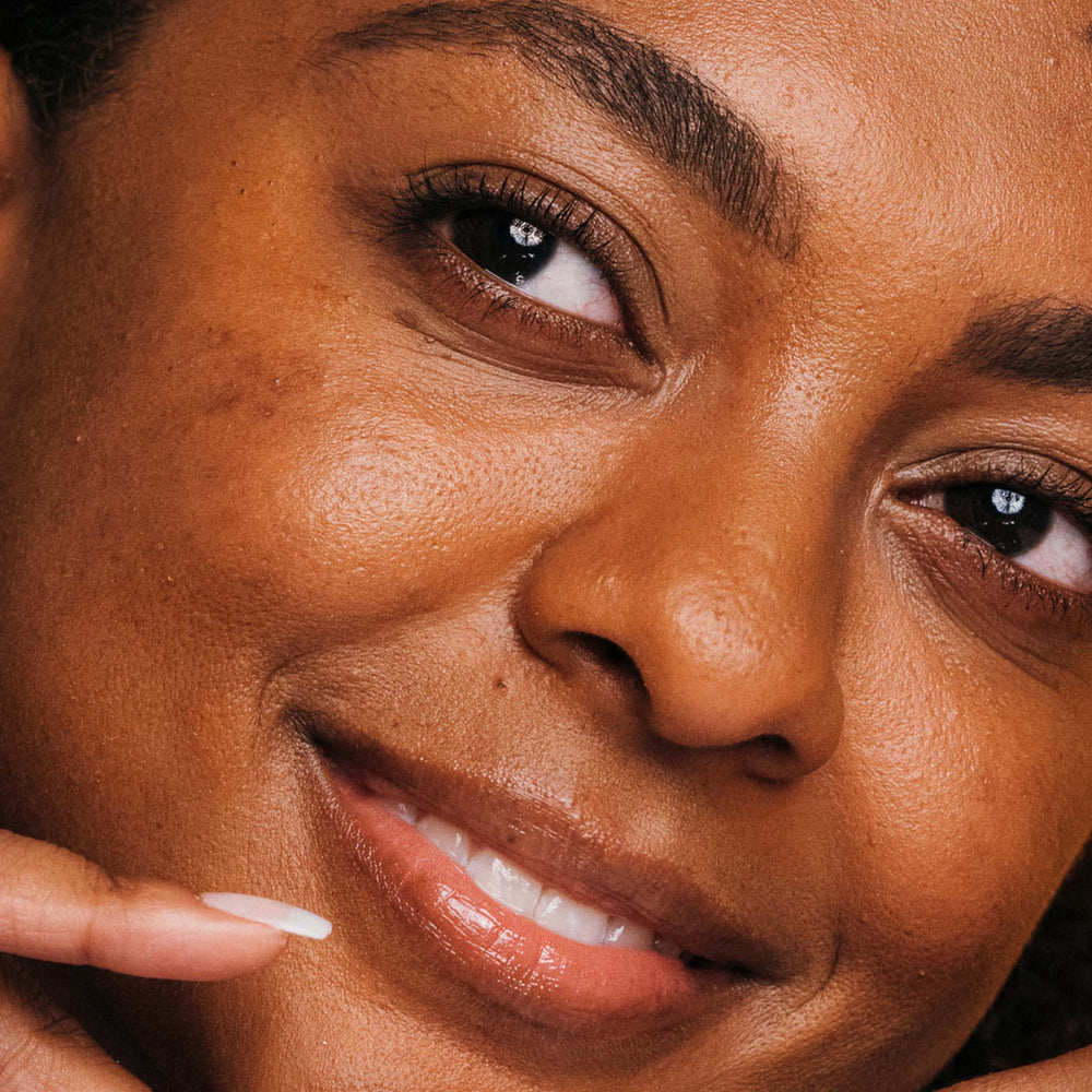 Close-up of a woman's face with a soft smile, focusing on her eyes and nose.