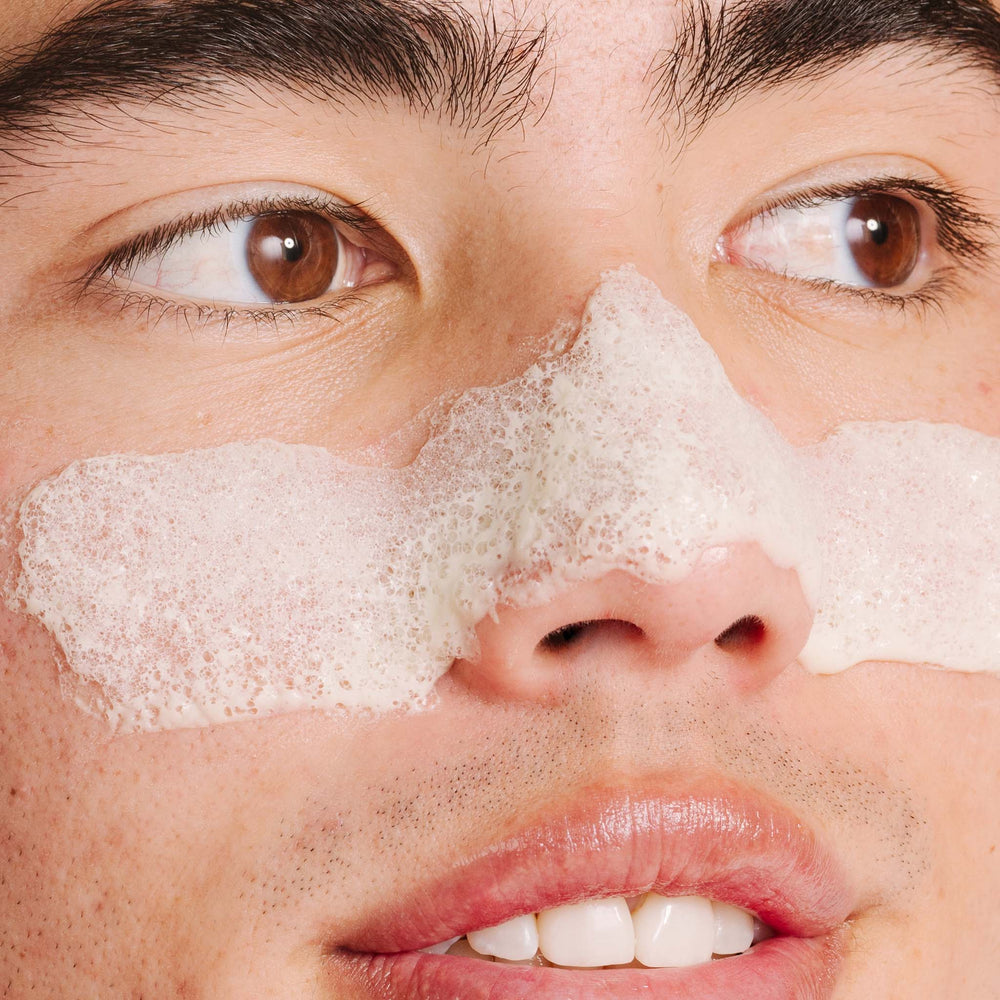 Close-up of a person with foam on their face, possibly after a skincare routine.