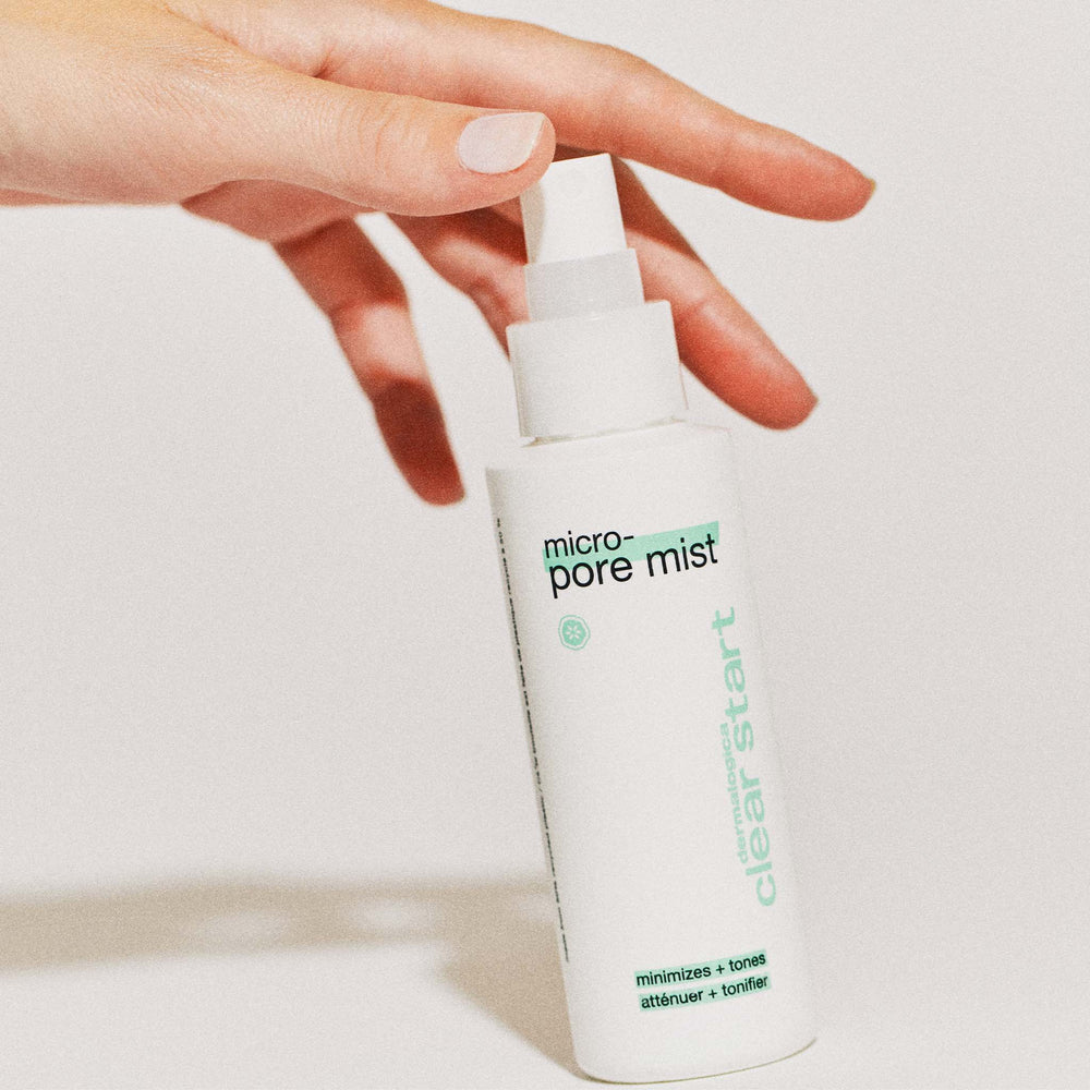 White bottle of 'micro pore mist' held by a hand against a light background