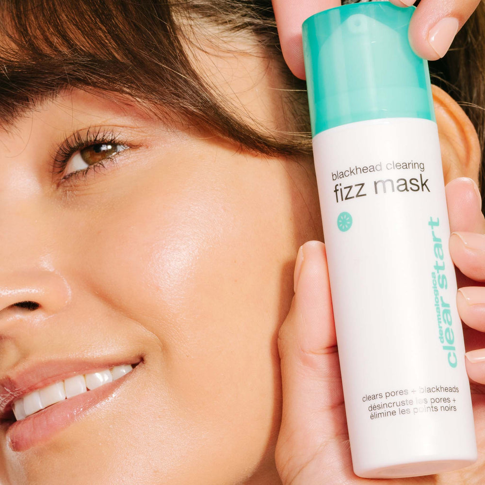 Person holding a 'clear start' blackhead clearing fizz mask bottle close to their face.