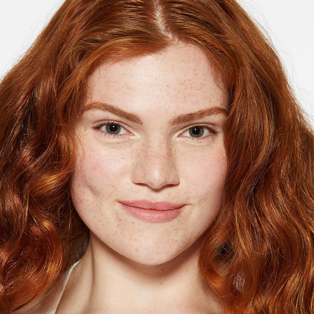 Close-up of a person with red hair and freckles on a white background