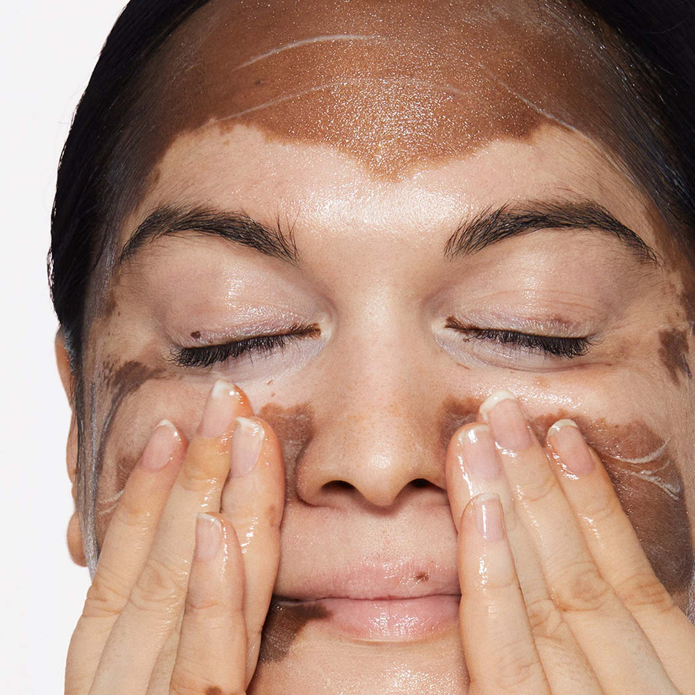 Close-up of a person applying phyto nature firming serum to their face with a neutral background
